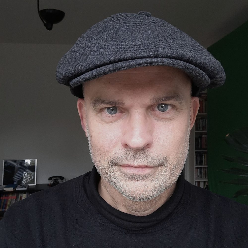 Vincent Boureau, Porträt mit Schiebermütze und Bart, ruhiger direkter Blick in die Kamera.